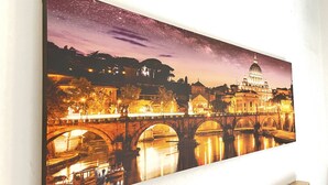 A framed painting of a cityscape at night with a bridge and a prominent building with a dome.