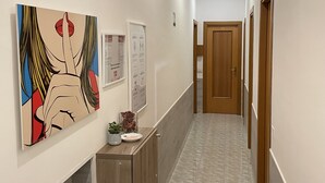 A hallway with a wooden cabinet, a framed artwork, and a door at the end.