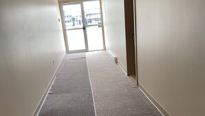 Un pasillo con suelos alfombrados, una puerta a la derecha y una señal de salida encima de la puerta.