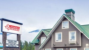Un edificio con el letrero de Canada’s Best Value Inn, que ofrece comodidades como desayuno continental de lujo, WiFi, piscina, bañera de hidromasaje y tobogán de agua.