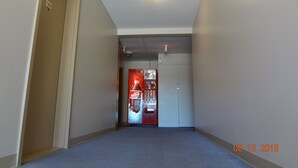 Un pasillo con una puerta marcada con el número 118 y una máquina expendedora con el logo de Coca-Cola.