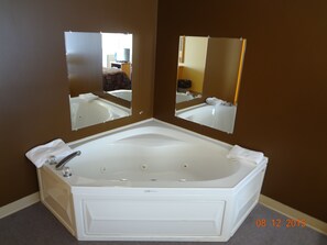 A bathroom with a large freestanding bathtub, two wall-mounted mirrors, and a towel rack.