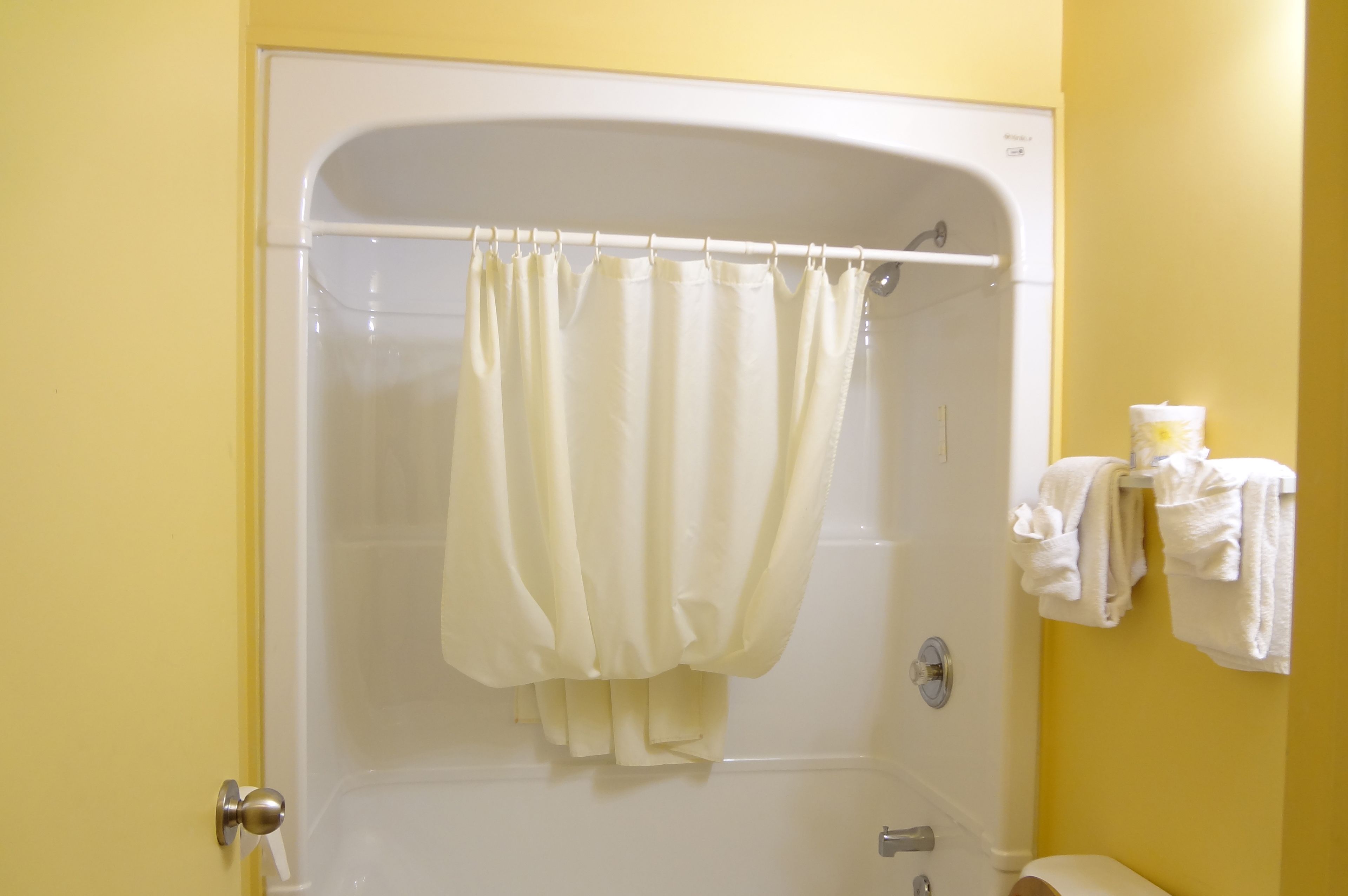 Un baño con ducha, inodoro y toallero con toallas.