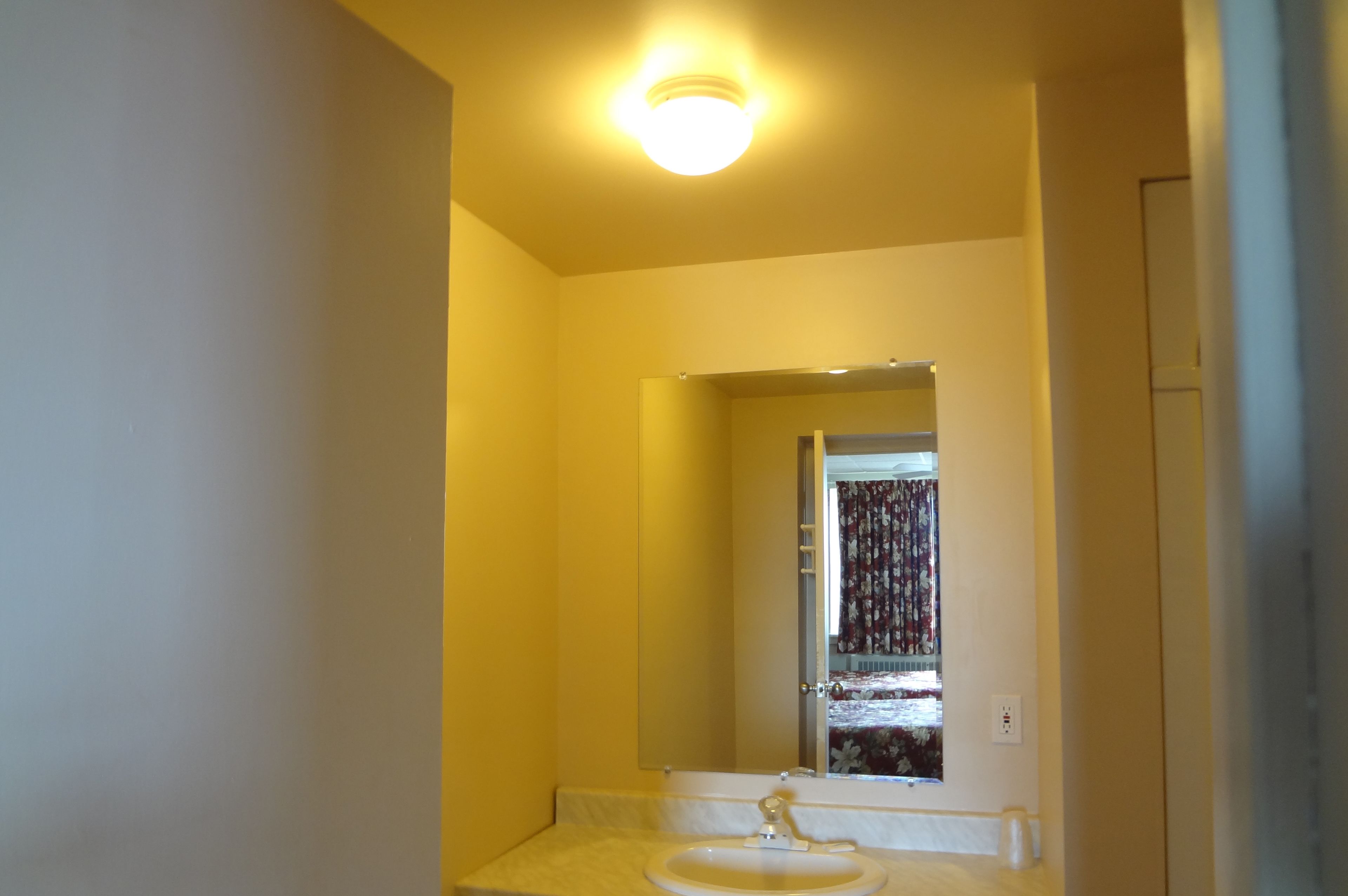 A bathroom with a white sink, a mirror, and a ceiling light.