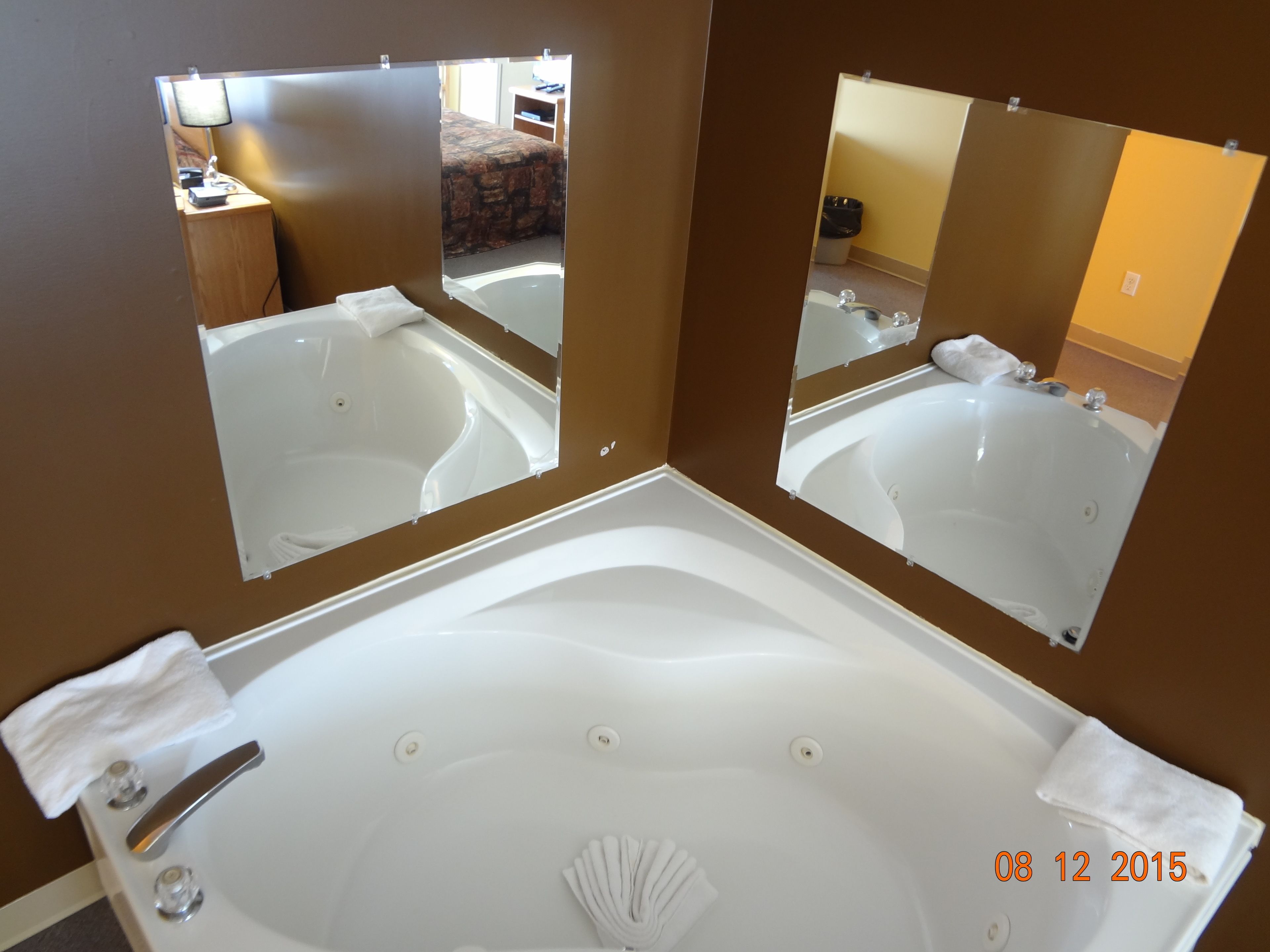 Un baño con una bañera blanca grande, dos espejos y un perchero para toallas.