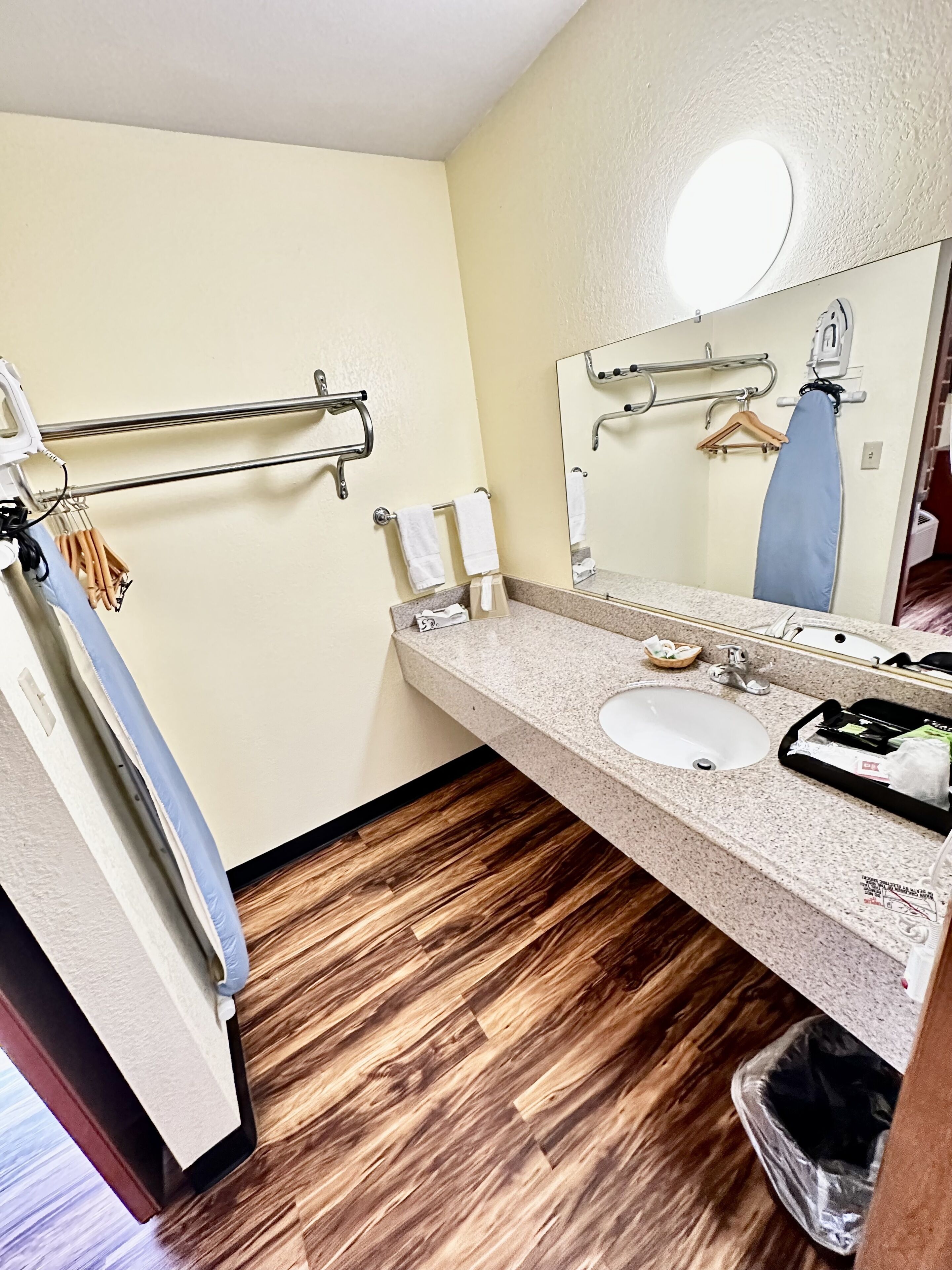 Un baño con lavamanos, espejo, toallero y suelo de madera.