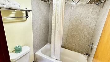 Et badeværelse med toilet, badekar og bruseforhæng.