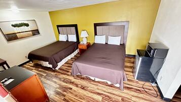 A hotel room with two beds, a desk, a chair, a TV, and a painting on the wall.