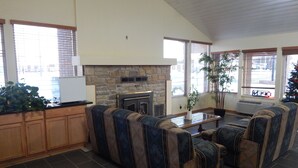 A spacious living area with a stone fireplace, a large window, and a seating area with patterned sofas. - Regency Inn lola Kansas (Iola)