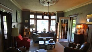 Amplia sala de estar con chimenea, un sofá, una mesa de centro y un sillón rojo.
