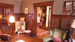 Una sala de estar acogedora con muebles de madera, una estantería y un sillón verde.