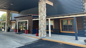 A modern building with a stone facade, large windows, and a covered outdoor seating area.