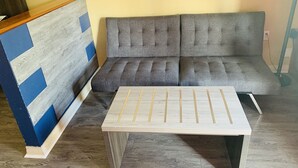 A room with a grey sofa, a wooden coffee table, and a blue and white patterned wall.