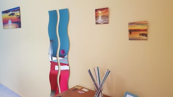 Una camera d'albergo con un letto, una scrivania e una parete con tre quadri.