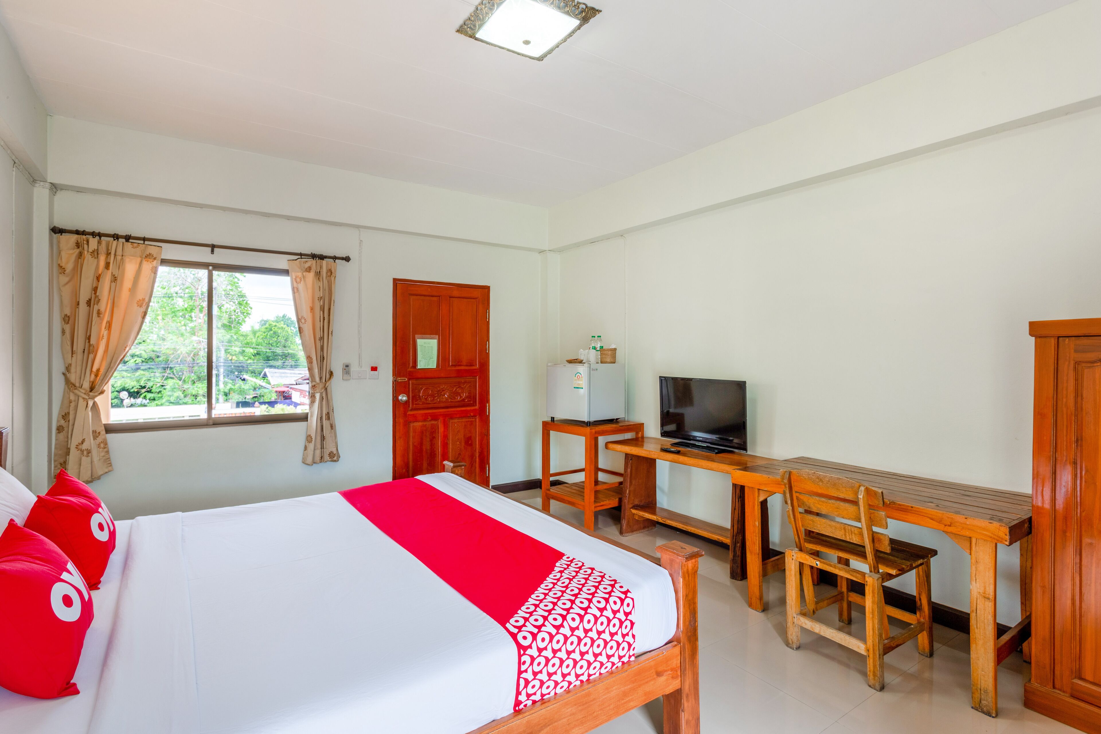 Una habitación de hotel con cama, escritorio, silla, televisor y armario.