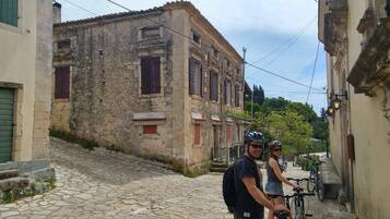 A narrow cobblestone street with historic stone buildings, a bicycle, and a person wearing a helmet.