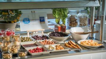 Un bufé con diversos alimentos, como frutas, nueces y pan.