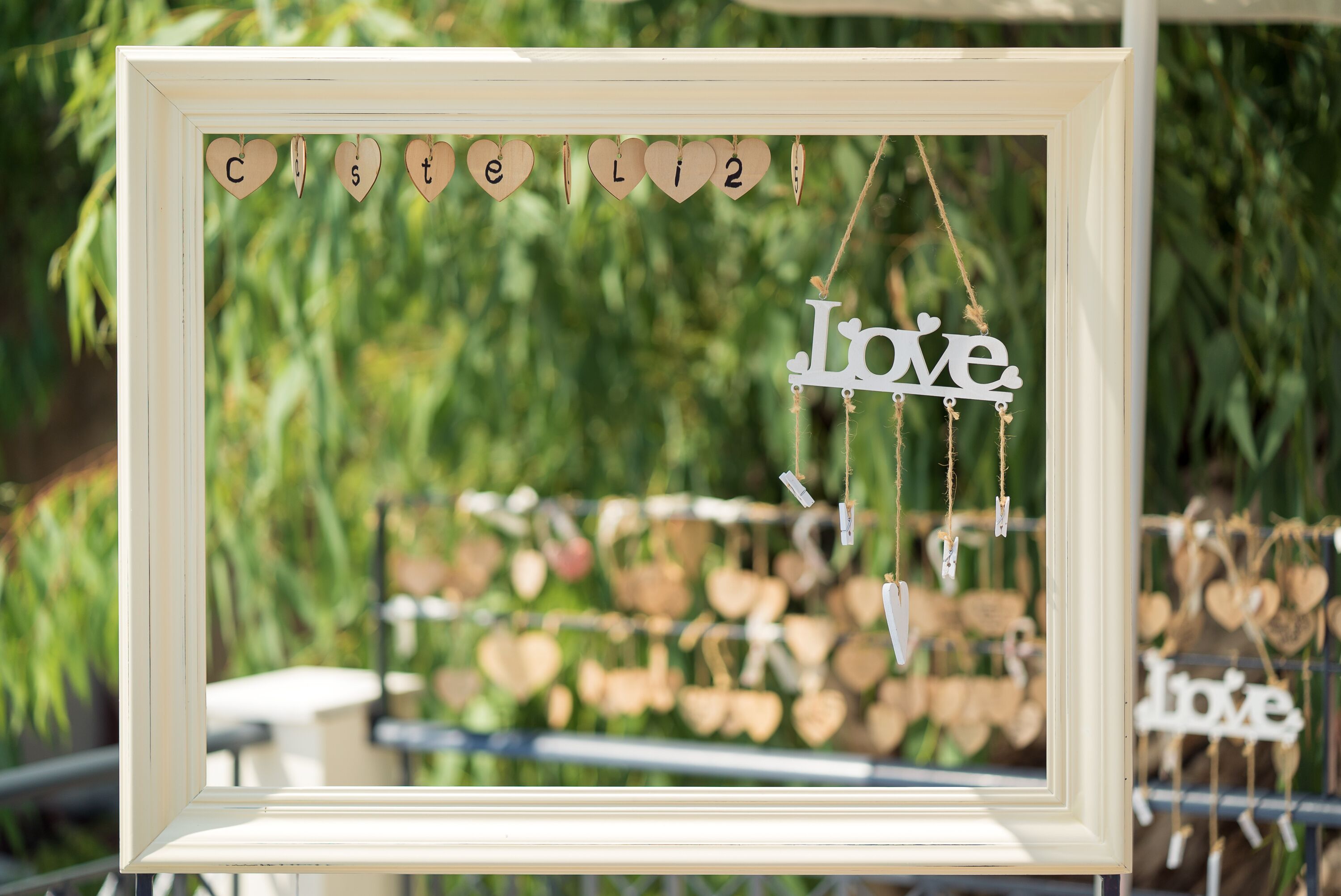 Une photo encadrée sur laquelle est inscrit le mot « Amour », suspendue devant un arrière-plan flou de verdure.