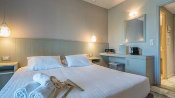 Habitación de hotel con una cama grande, dos mesitas de noche, un escritorio con silla, un espejo y una puerta que da a un baño.
