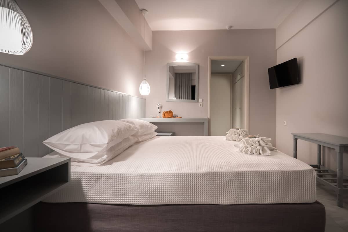 Una camera da letto moderna con un grande letto, un comodino e una TV a parete.