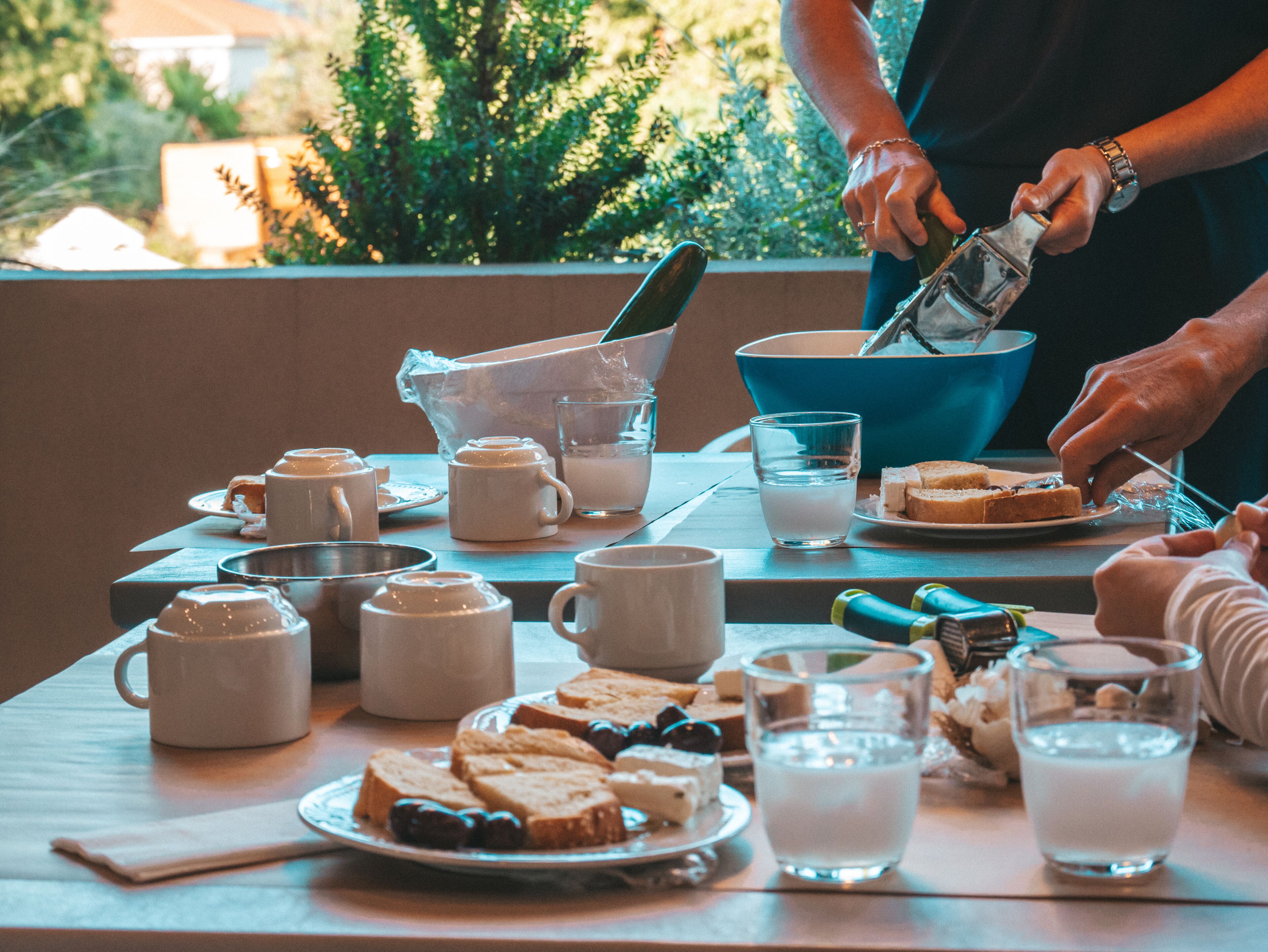 A breakfast table with various food items and drinks, including bread, pastries, and milk.