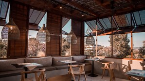 A modern interior with wooden furniture, large windows, and hanging light fixtures. - Castelli Hotel Adults Only - All Inclusive (Zakynthos)