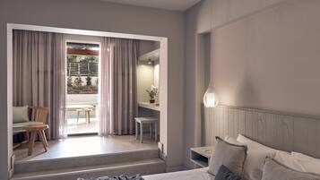 A modern hotel room with a bed, a desk, and a view of a pool and garden.