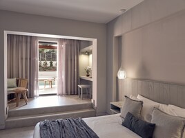 Una camera d'albergo moderna con un letto, una scrivania e vista su piscina e giardino.