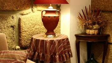 Ein gemütliches Wohnzimmer mit Steinwand, einem Tisch mit Lampe, einer Couch und einem kleinen Beistelltisch mit Dekoration.