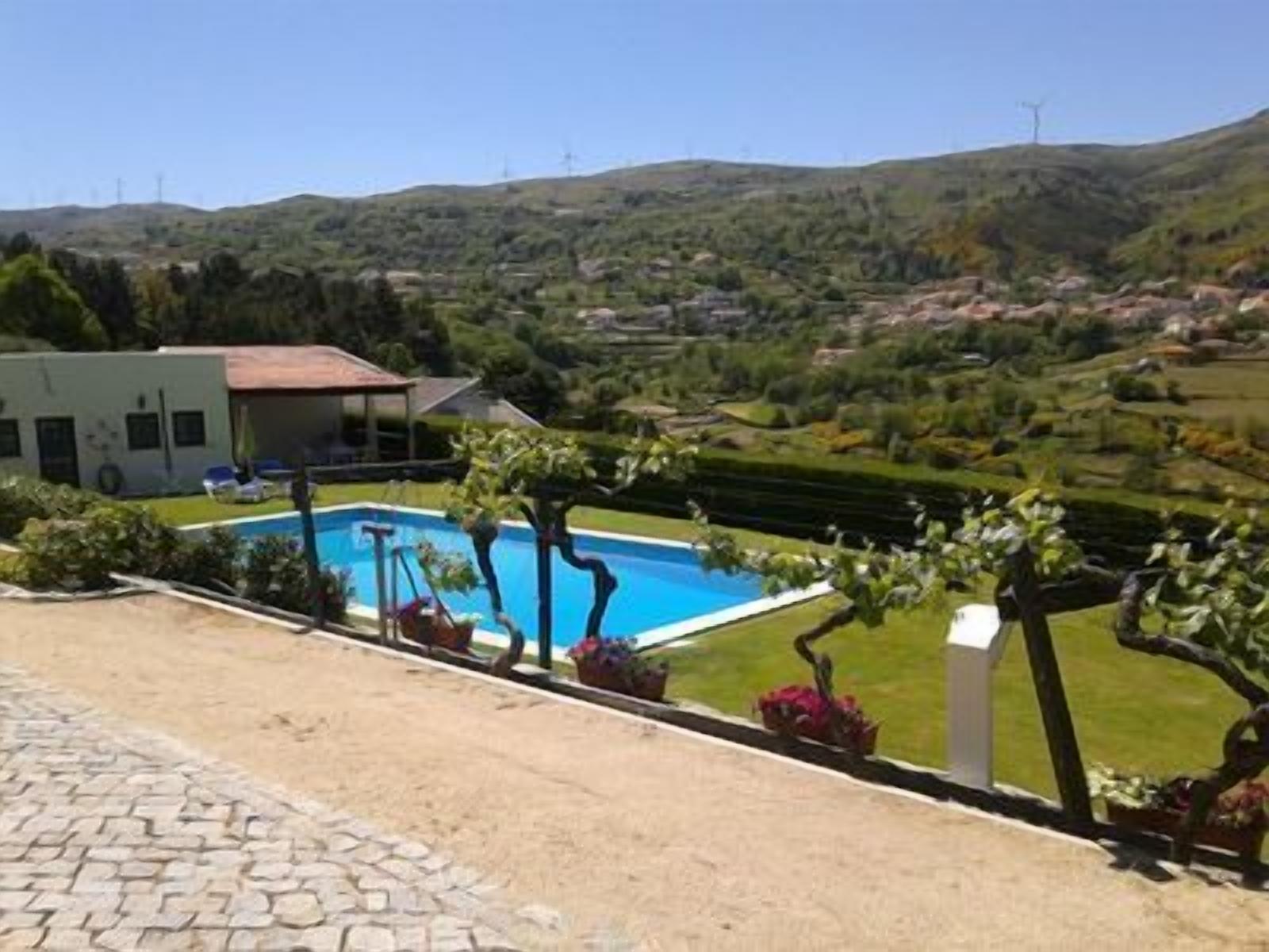 A poolside area with a clear view of the surrounding landscape, including hills and wind turbines in the distance.