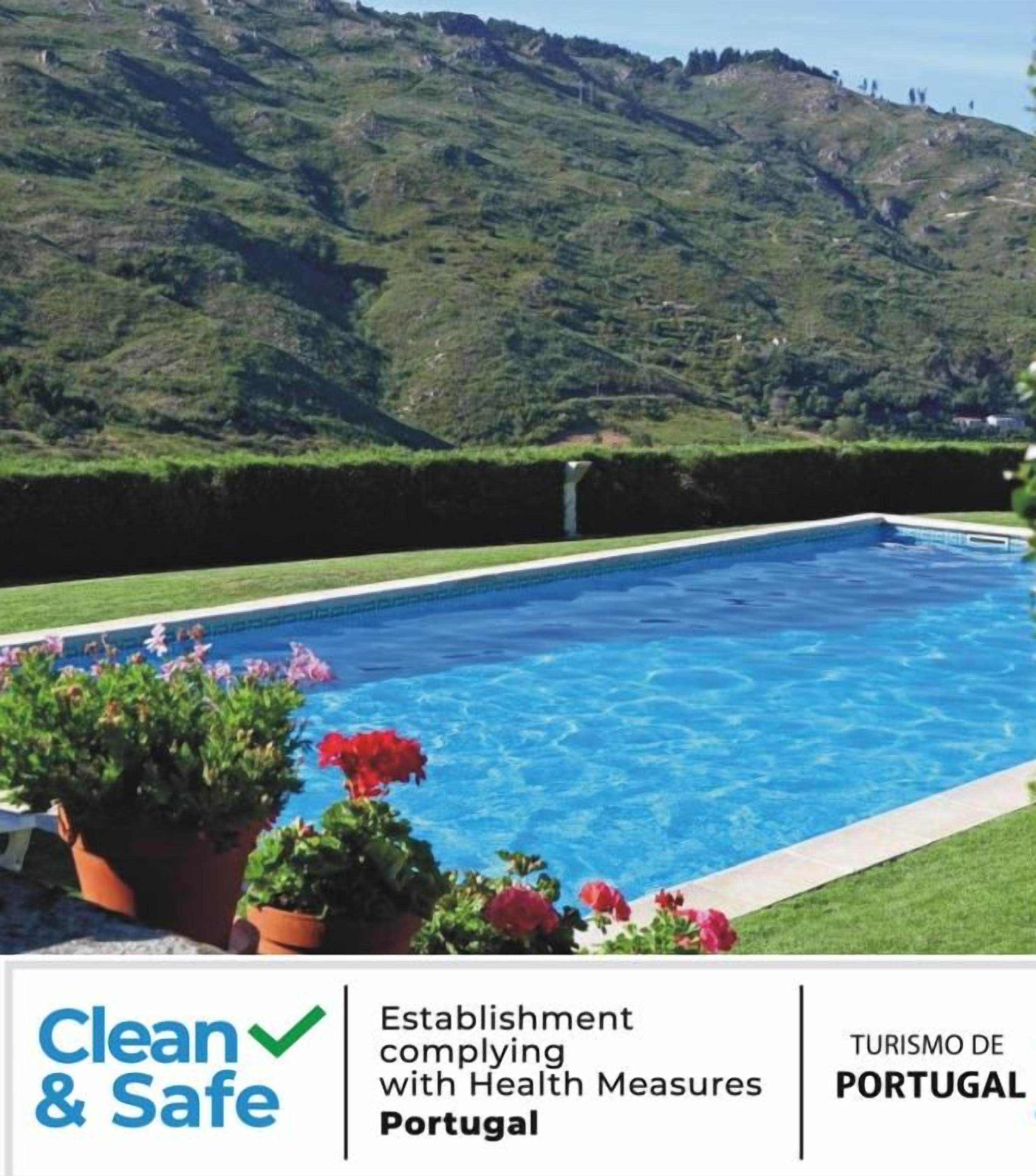 Una piscina con vistas a colinas verdes y un cielo despejado.