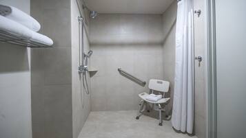 A small, modern bathroom with a shower, a grab bar, and a wheelchair-accessible toilet.