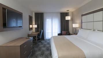 Habitación de hotel con cama, escritorio, silla y televisor instalado en la pared.