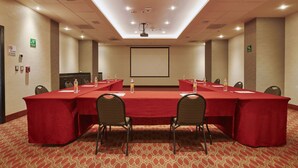 Une salle de conférence équipée d’une longue table, de chaises et d’un écran de projection.