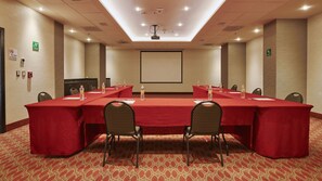 Une salle de conférence équipée d’une longue table, de chaises et d’un écran de projection.