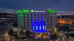 Un hotel Holiday Inn Express & Suites con fachada moderna, varios pisos y una zona de estacionamiento.