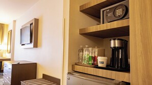 Une chambre d’hôtel équipée d’un mini-bar, d’un téléviseur fixé au mur et d’une machine à café posée sur le comptoir.