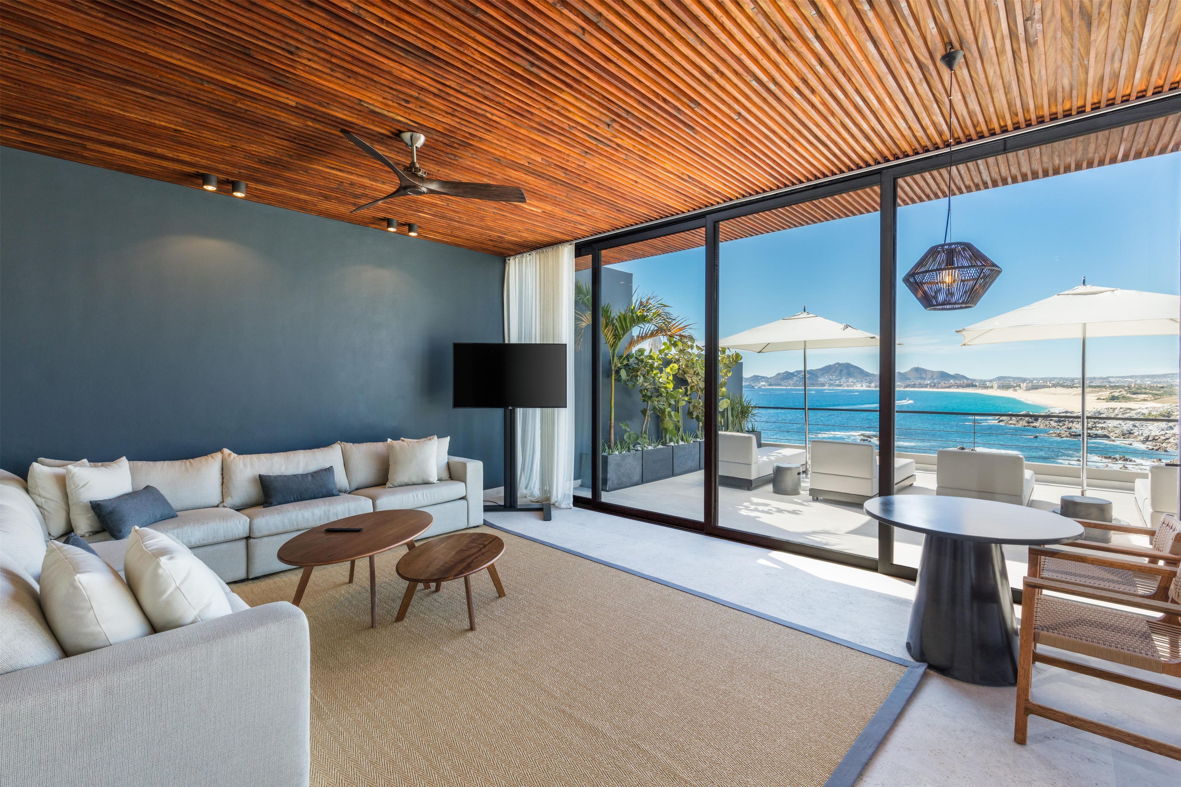 A modern living room with a large window overlooking a beach and ocean.