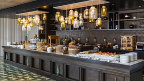 A buffet setup with hanging light fixtures, a variety of food items, and a patterned floor. - The Cape, A Thompson Hotel, by Hyatt (Cabo San Lucas)