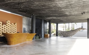 A spacious lobby with a wooden reception desk, a unique sculpture, and a view of the outdoors.