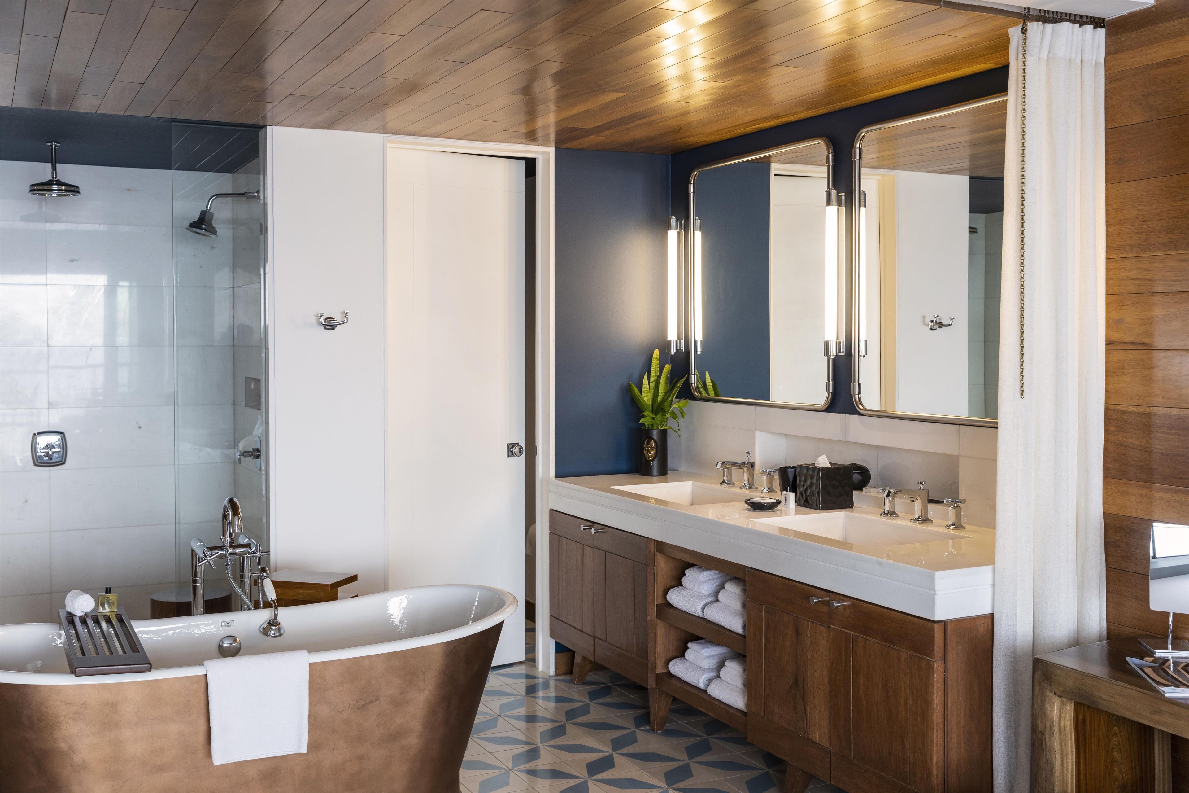 Une salle de bain moderne avec une baignoire sur pieds, un grand miroir et une cabine de douche.
