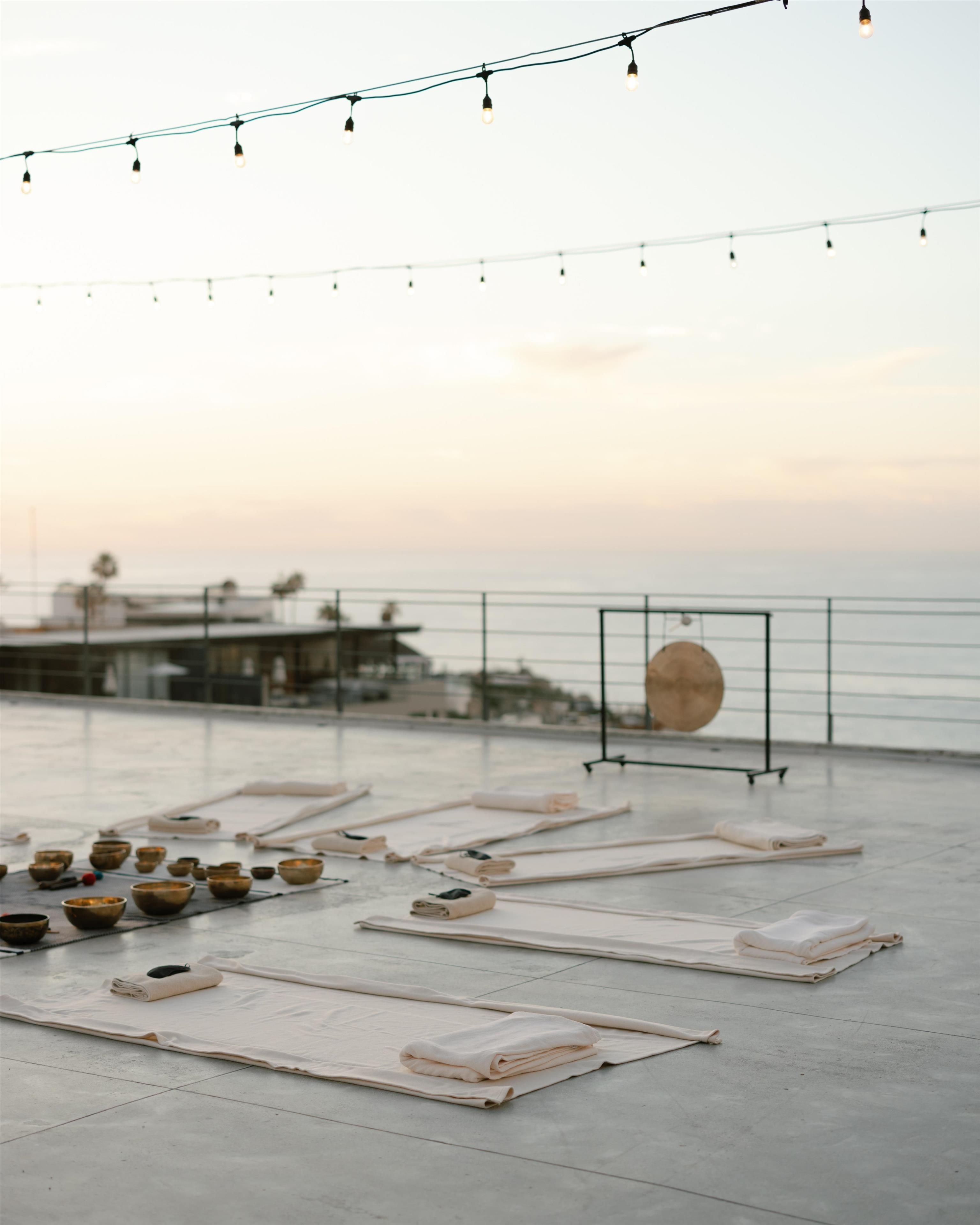 A rooftop terrace with mats and bowls arranged for a yoga session, overlooking a body of water.