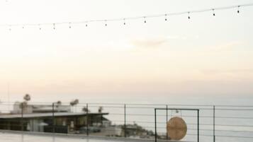 A rooftop terrace with mats and bowls arranged for a yoga session, overlooking a body of water.