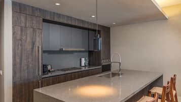 A modern kitchen with dark wood cabinetry, a stainless steel range hood, and a large island with a sink.