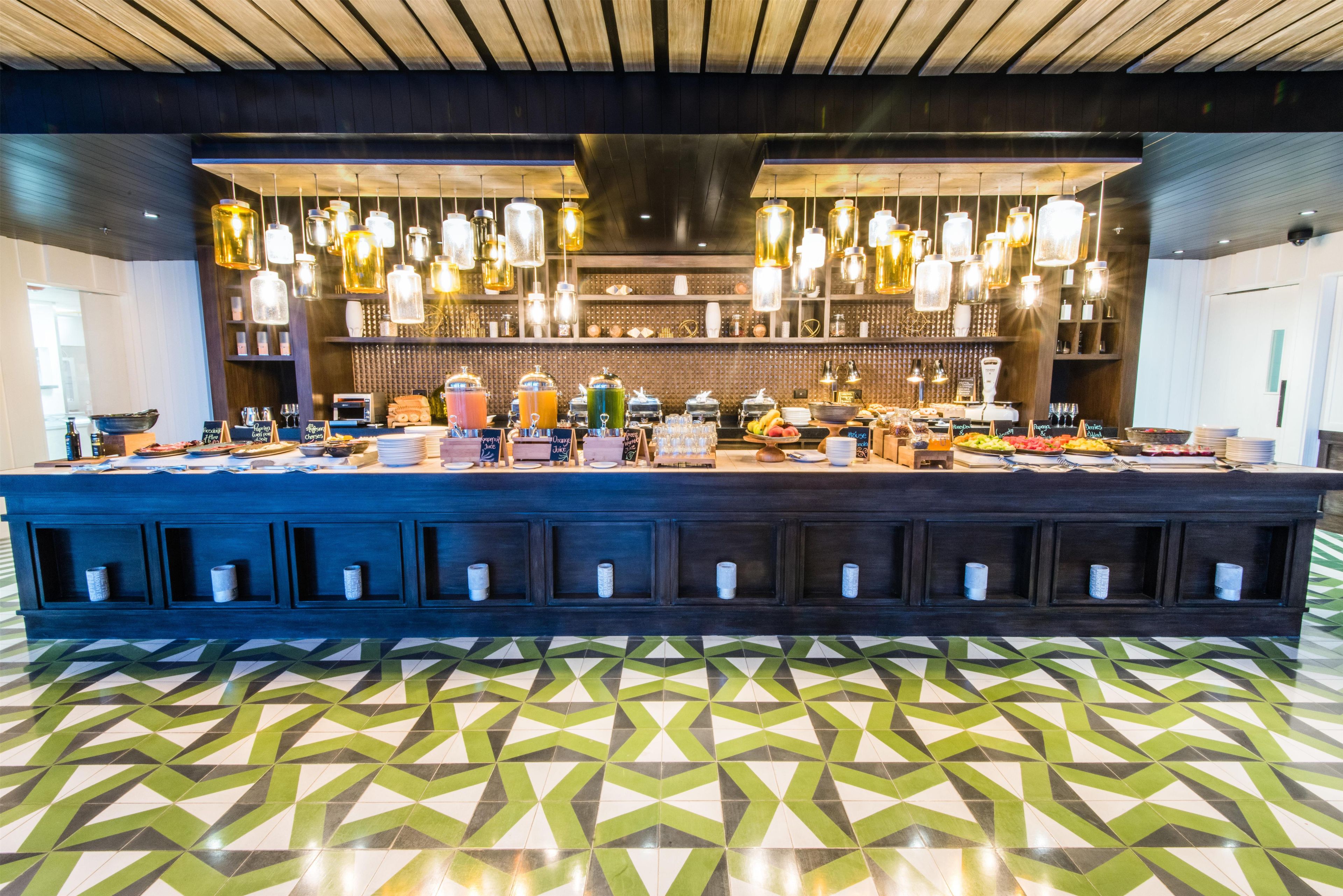 A bar area with a long counter, hanging lights, and a patterned floor.