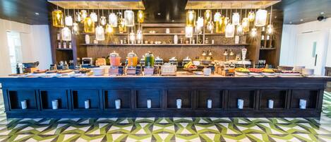 A bar area with a long counter, hanging lights, and a patterned floor.