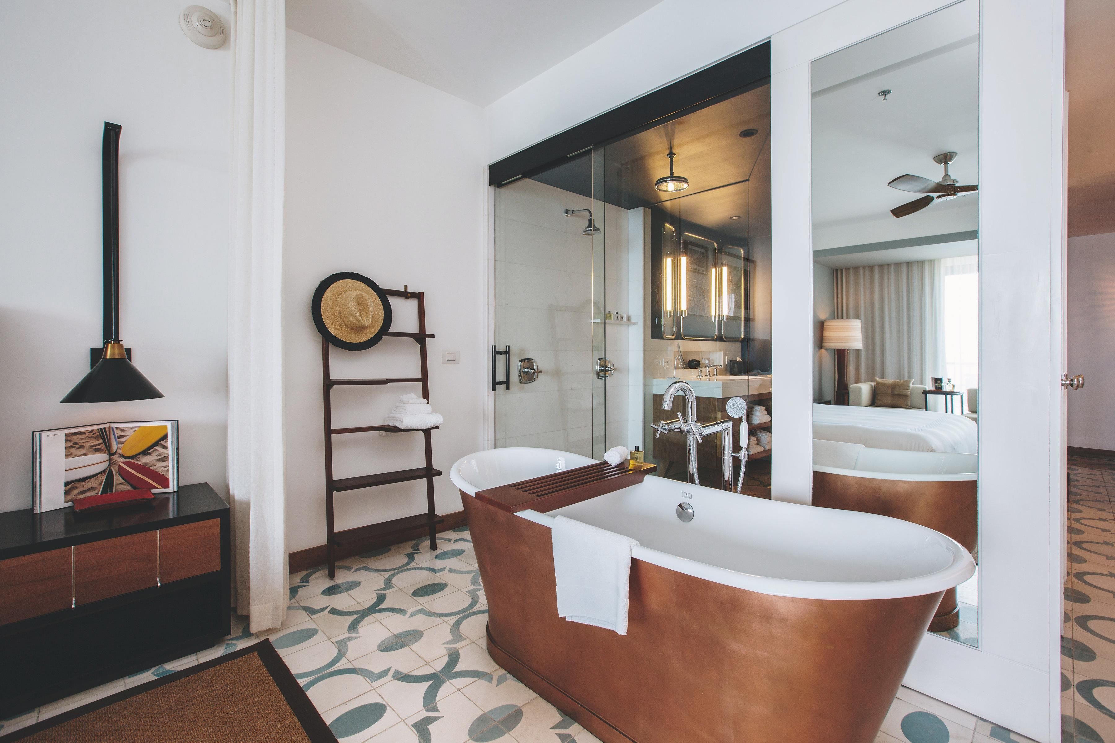 A modern bathroom with a freestanding bathtub, a towel rack, and a mirror reflecting the room.