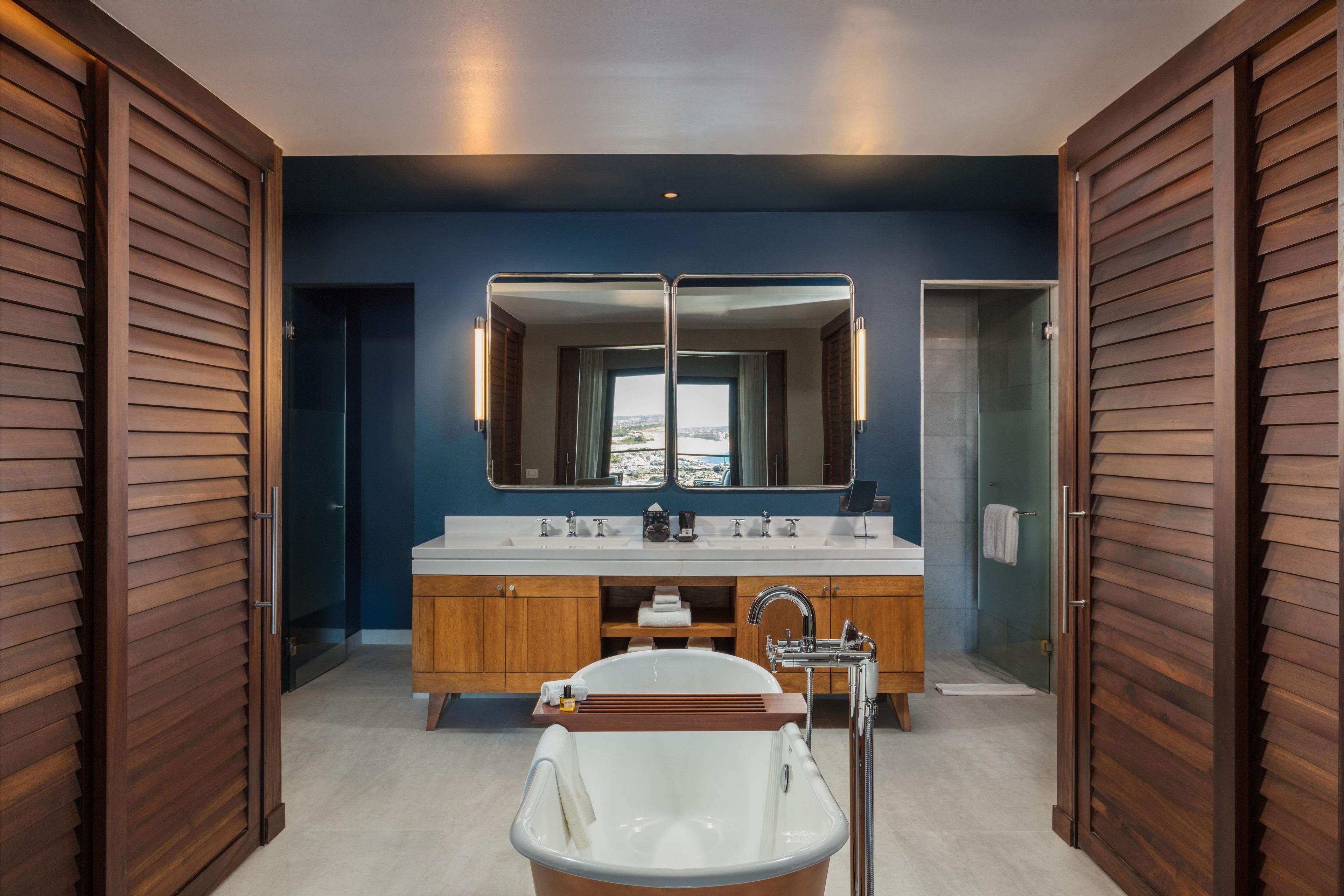 A modern bathroom with a freestanding bathtub, a large mirror, and a dual sink vanity.