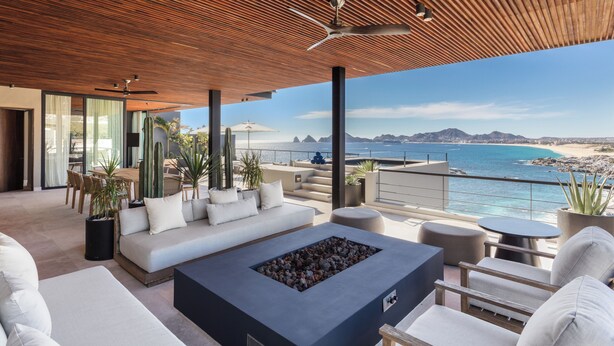 A modern outdoor living space with a wooden ceiling, a fire pit, and a view of the ocean. - The Cape, A Thompson Hotel, by Hyatt (Cabo San Lucas)