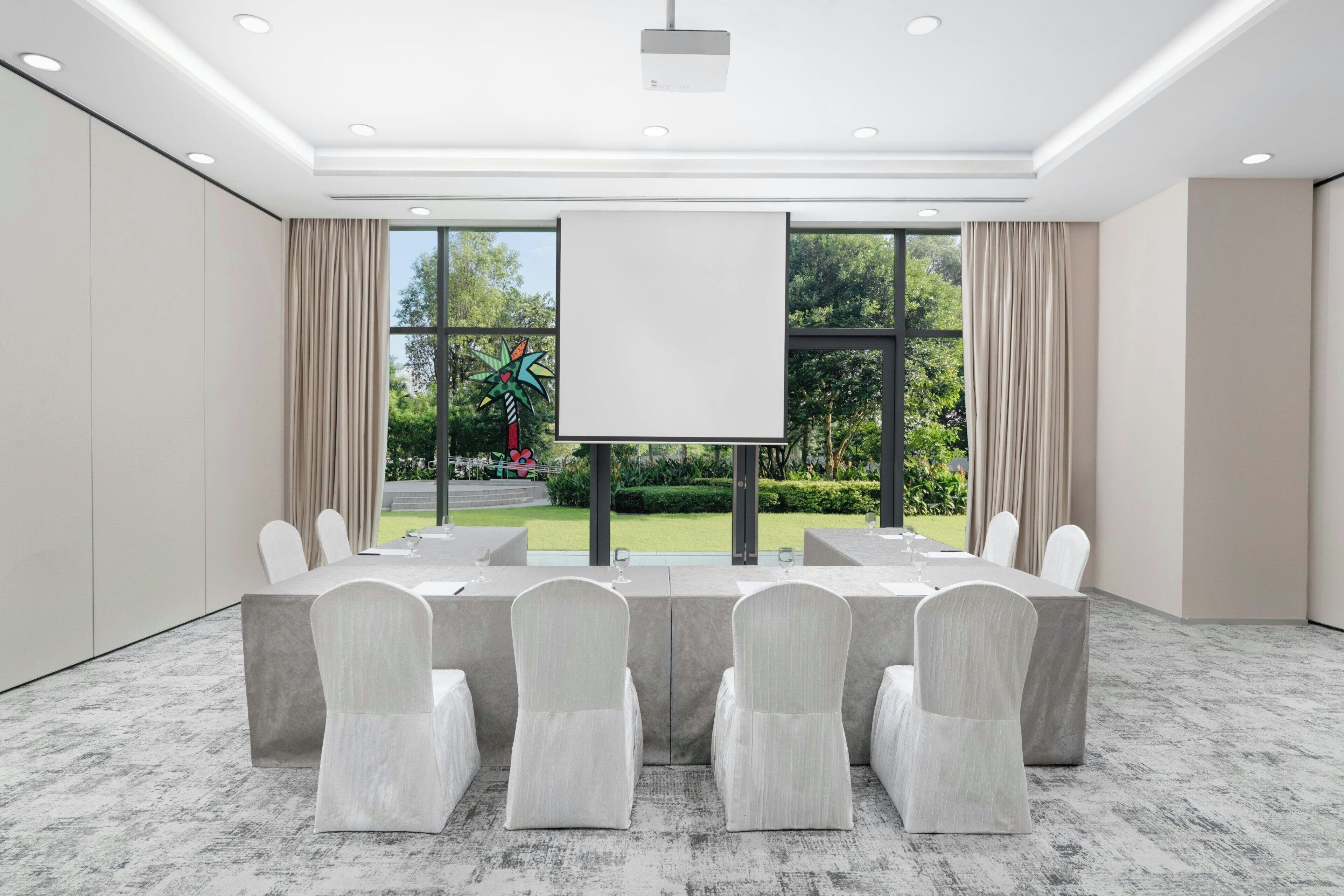 A conference room with a large table, chairs, and a projector screen.